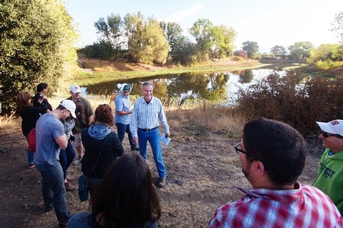 Group of people on a guided tour near a pond in Lodi, California, during late afternoon.