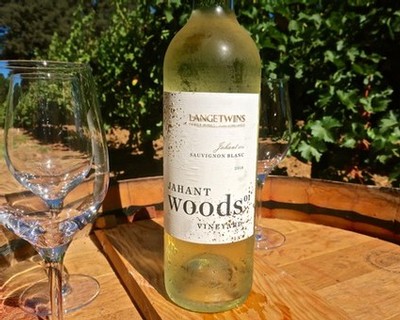 A bottle of Sauvignon Blanc wine from Lodi Winegrape Commission on a wooden table outdoors.