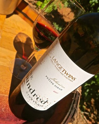 Close-up of a Lodi Winegrape Commission wine bottle with a glass of red wine in the background.