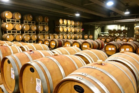 Wine barrels stored in a cellar, part of the Lodi Winegrape Commission's wine production process.