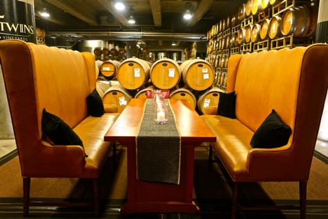 Elegant tasting room with high-backed orange booths and wine barrels in the background.