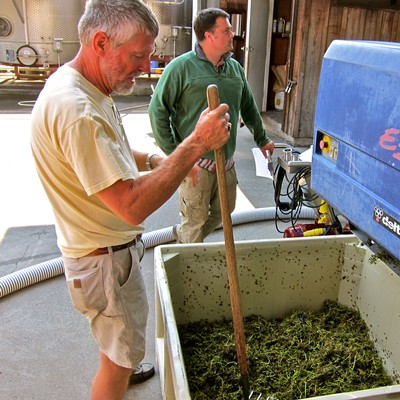 Two men working with winegrape processing equipment at Lodi Winegrape Commission.