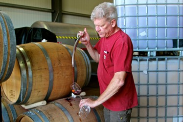 Winemaker tasting wine from barrels at Lodi Winegrape Commission facility.