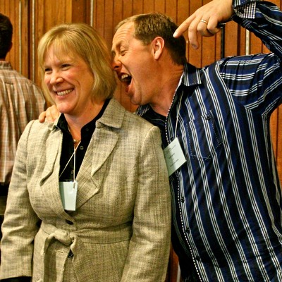 Two people smiling and enjoying a lively conversation at a Lodi Winegrape Commission event.