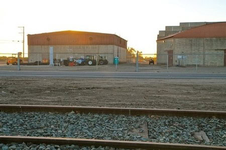 View of Lodi Winegrape Commission building with industrial structures and train tracks in foreground.