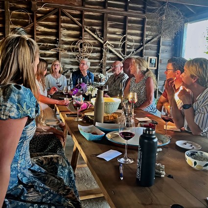 Group of people gathered around a table discussing wine and grape growing at a Lodi Winegrape Commission event.