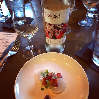 Bottle of Bokisch wine on a restaurant table with glasses and a plated dish.