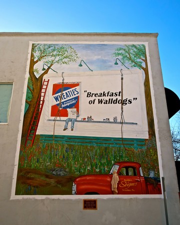 Colorful mural depicting Walldogs painting a sign for Wal-Mart with trees and a red truck in Walnut Grove, California.