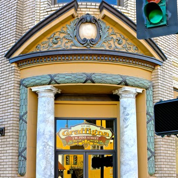 Elegant entrance of Craftigona wine bar with classical columns and ornate architectural details.