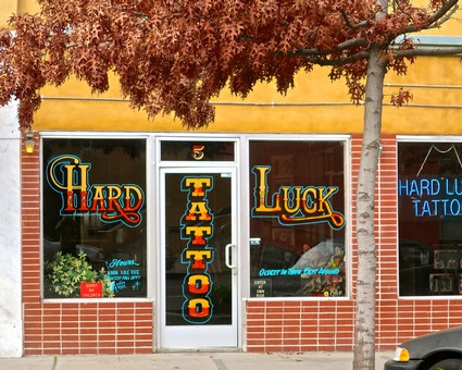 Facade of a tattoo shop with colorful signs reading 'Hard Luck' and 'Tattoo' in Lodi, California.