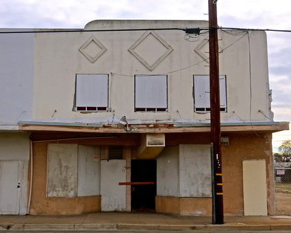 Old abandoned building with boarded windows and a utility pole in Lodi, California.
