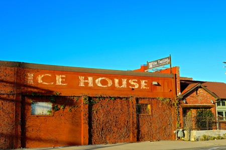 Rusty building with faded sign reading 'Ice House' under a clear blue sky.