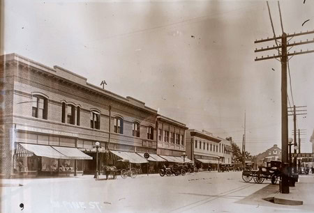 Vintage photo of historic downtown Lodi with old storefronts and horse-drawn carriages.