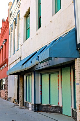 Exterior view of the Lodi Winegrape Commission office with colorful boarded-up windows and a blue awning.