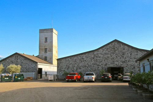 Lodi Winegrape Commission building with parking lot and stone structures under a clear blue sky.