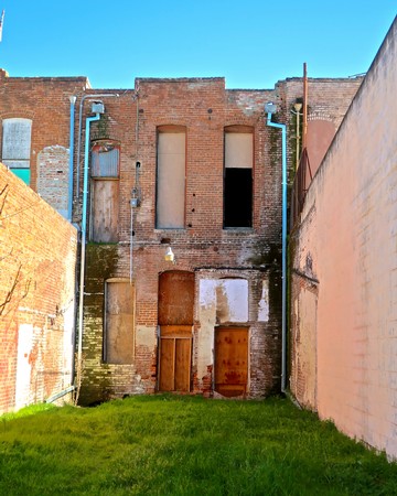 Old brick building with boarded windows and fire escapes in Lodi, California.