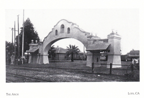 Historic arch at Lodi Winegrape Commission in Lodi, California, with palm trees and railway tracks nearby.