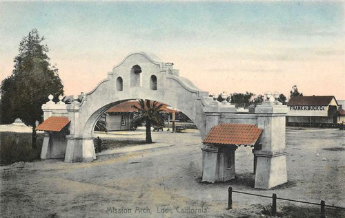 Historic Mission Arch in Lodi, California, with white stucco and red-tiled roof structures.