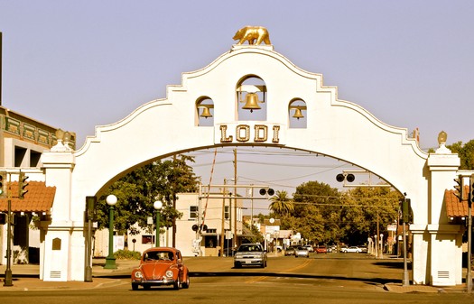 Historic Lodi entrance arch with bell and golden bear statue, representing the Lodi Winegrape Commission in California.