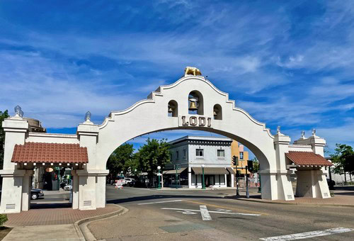 Historic archway in Lodi, California, representing the Lodi Winegrape Commission, under a bright blue sky.