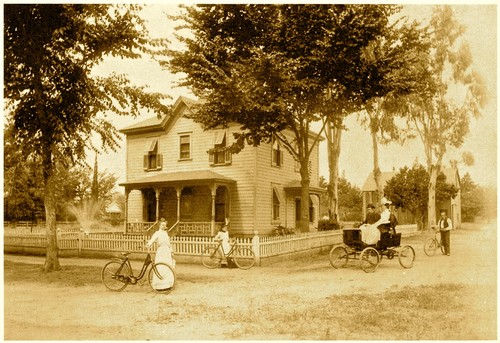 Vintage photo of people with bicycles and horse-drawn carriage in front of a house, representing Lodi wine history.