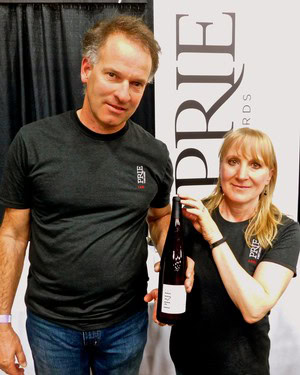 Two people holding a wine bottle at a Lodi Winegrape Commission event, smiling for the camera.