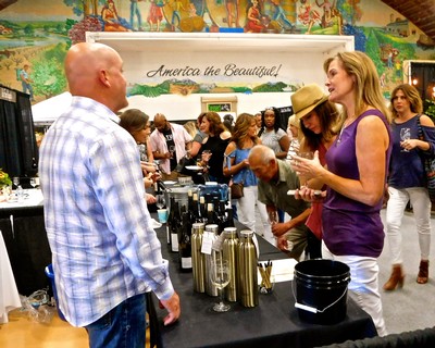 People tasting wine at a Lodi Winegrape Commission event with a colorful mural background.