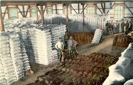 Workers in a warehouse storing large sacks of winegrapes in a historic building.