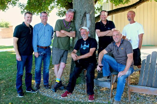 Group of seven men outdoors under a tree, smiling and posing for a photo, representing the Lodi Winegrape Commission.