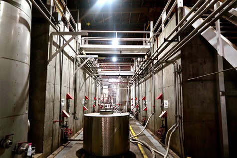 Interior view of a wine production facility with pipes, tanks, and industrial equipment in Lodi, California.