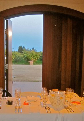 Interior view of a dining table set for a meal with a scenic outdoor landscape visible through an open door.