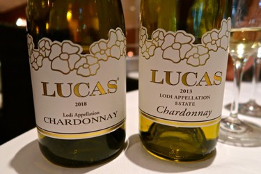 Two bottles of Lodi Chardonnay wine from 2013 and 2018 with wine glasses in the background.