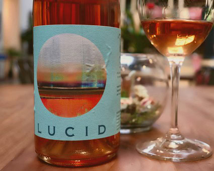 Close-up of a wine bottle labeled Lodi with a glass of rosé wine on a wooden table.