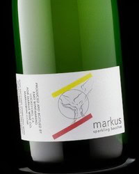 Close-up of a green sparkling wine bottle from Lodi Winegrape Commission with a white label and colorful accents.