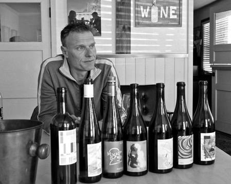 Man tasting wine at Lodi Winegrape Commission with bottles displayed on table.