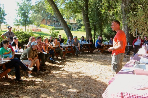 Group of people attending an outdoor event organized by the Lodi Winegrape Commission in a park setting.