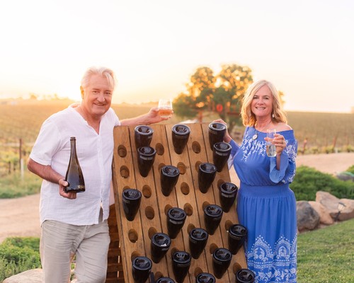 Smiling couple enjoying wine tasting outdoors at Lodi Winegrape Commission event.