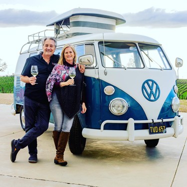 Happy couple enjoying wine tasting next to a vintage Volkswagen van at Lodi Winegrape Commission.