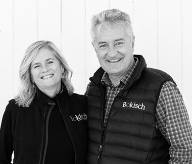 Two smiling individuals wearing Bokisch branded clothing, standing together in a professional setting.