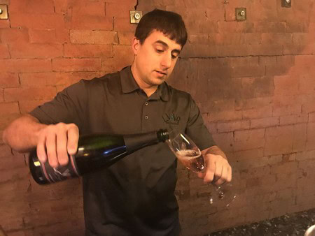 Man pouring wine into a glass at a Lodi wine tasting event, showcasing local winegrapes and wine production.