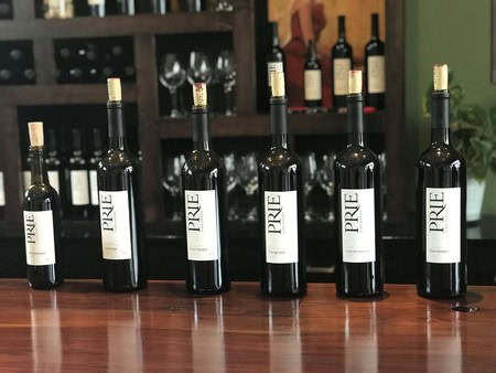 Six bottles of wine from the Lodi Winegrape Commission displayed on a wooden table.