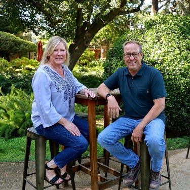 Two members of the Lodi Winegrape Commission sitting outdoors in a lush garden setting.