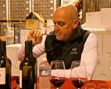 Man tasting wine at a Lodi Winegrape Commission event with bottles and glasses on the table.