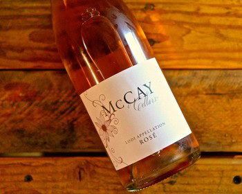 Lodi Winegrape Commission Rosé wine bottle on wooden surface, showcasing local wine production.