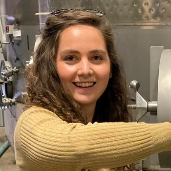 Woman smiling at a winegrape processing facility, representing Lodi Winegrape Commission activities.