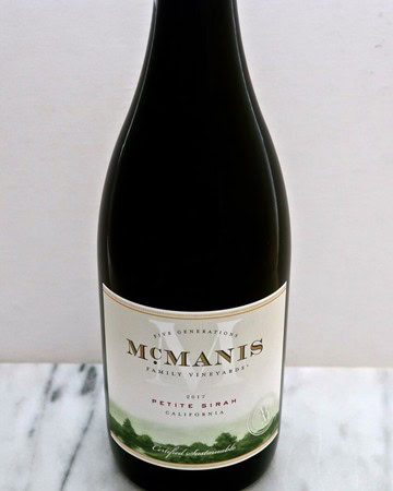 Close-up of McManis Petite Sirah wine bottle from California on a marble surface.