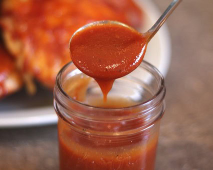 Close-up of tomato sauce being spooned from a jar, showcasing fresh, rich, and vibrant red color.