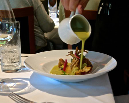 Chef pouring green sauce over gourmet dish at Lodi Winegrape Commission event.