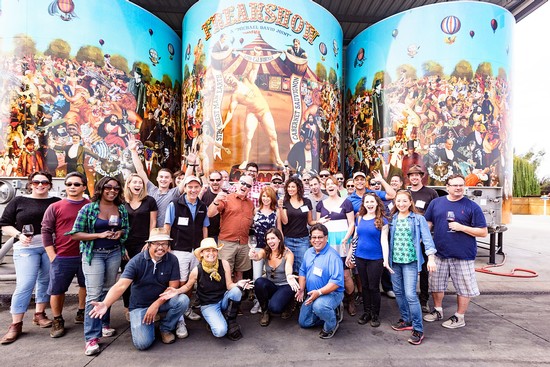 Group of people at Lodi Winegrape Commission event with colorful mural background.