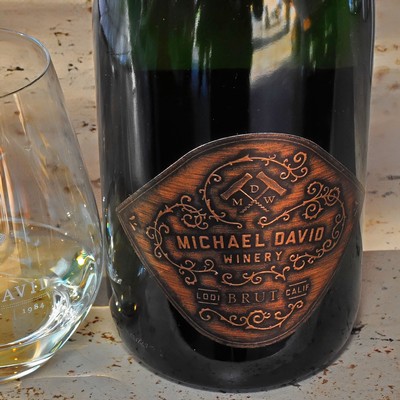 Close-up of a wine bottle from Lodi Winegrape Commission with a vintage label and glass of white wine.